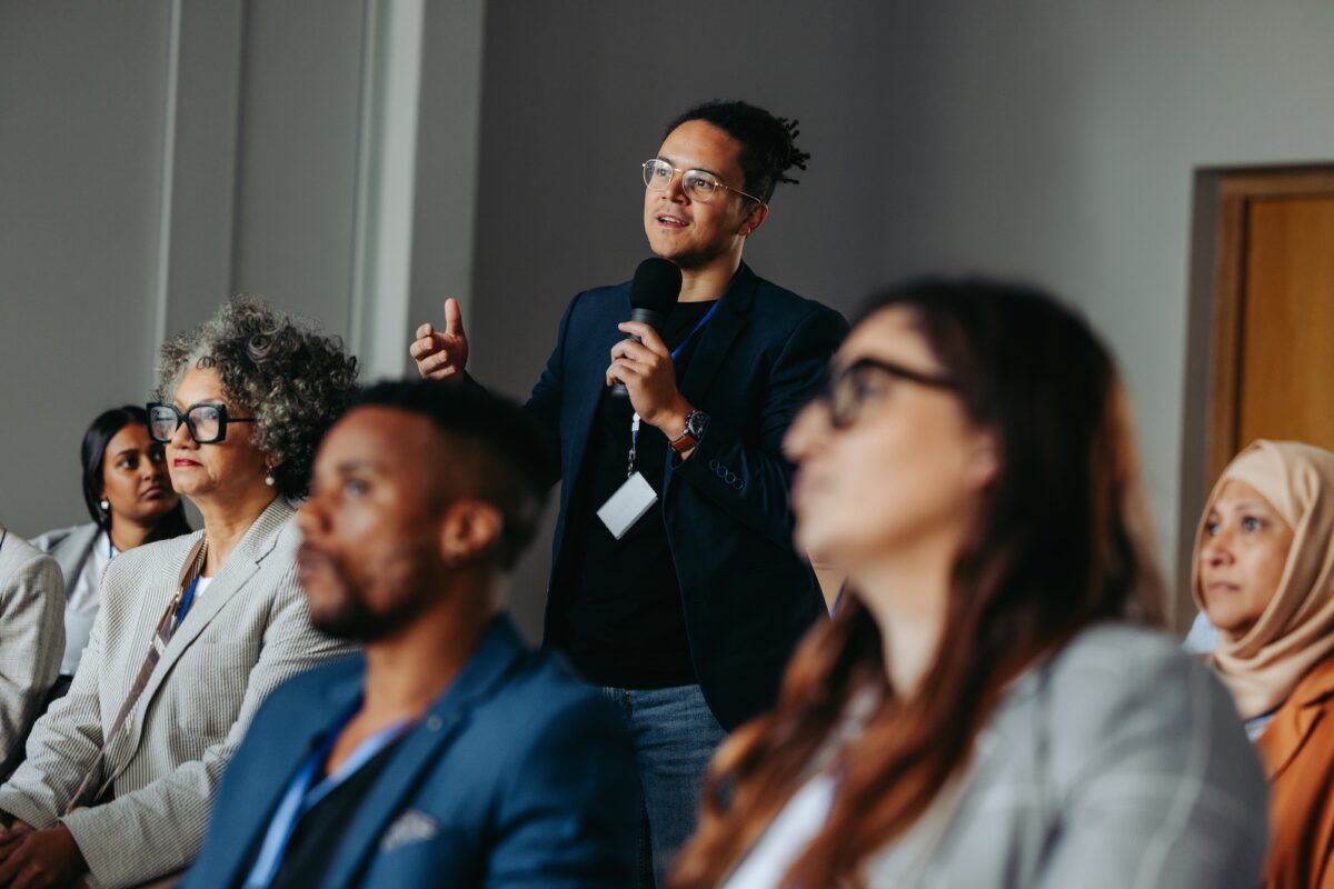 Businessman,Asking,A,Question,During,A,Diverse,Conference,Workshop,Presentation.
